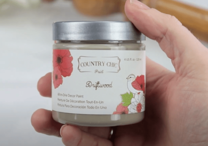 up close photo of someone holding a small jar of driftwood paint from country chic paint