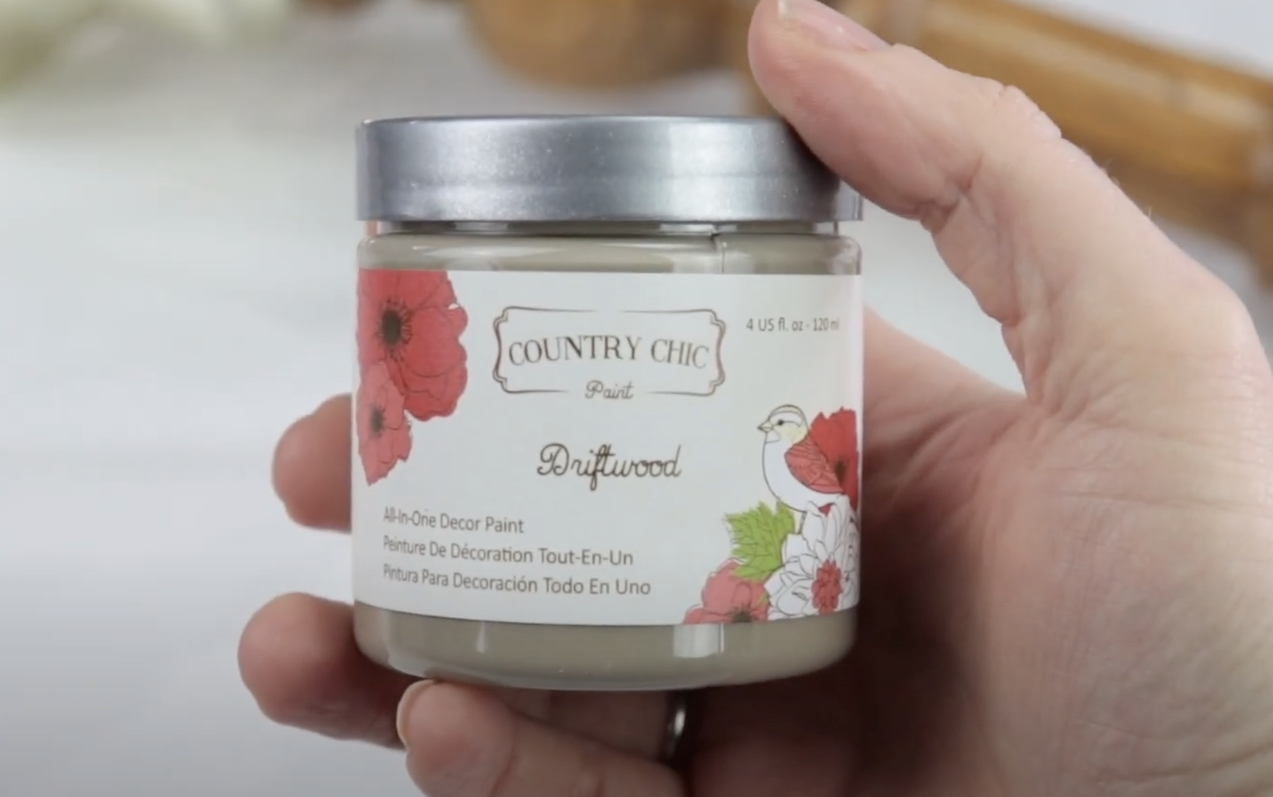up close photo of someone holding a small jar of driftwood paint from country chic paint