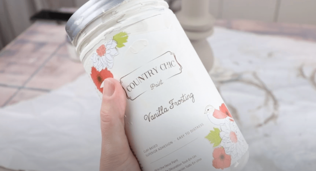 up close photo of someone holding a jar of country chic paint in the colour vanilla frosting