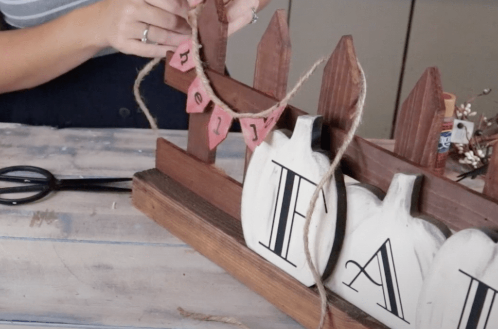 woman attaching a hello pendant banner to a diy fall sign