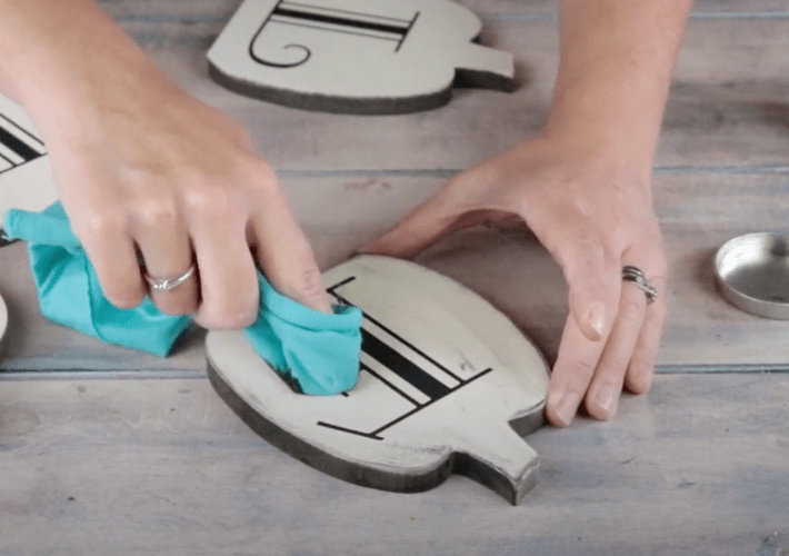rubbing grey wax onto a fall pumpkin sign