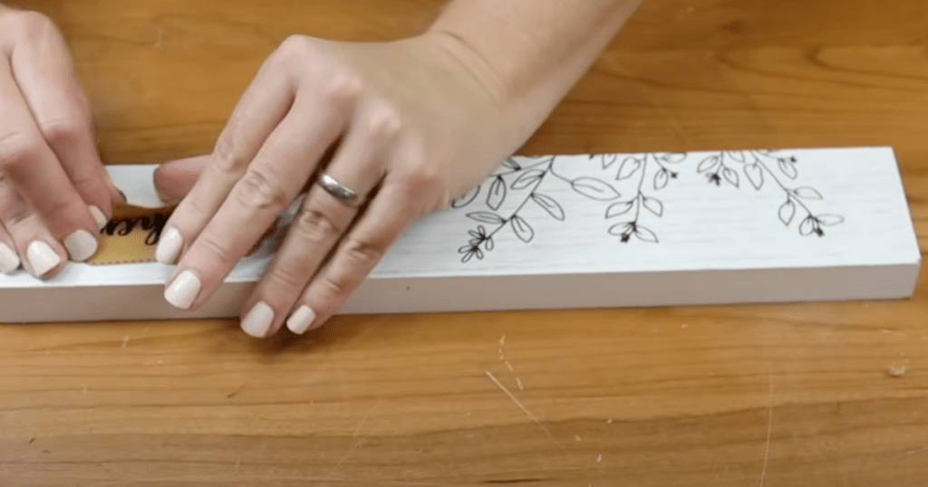 removing a small leather tag from a piece of mdf decor that is from dollar tree diy christmas ideas ornaments